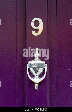 House number 9 on a purple door with silver door knocker Stock Photo