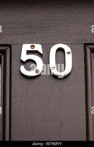 House number 50 in silver metal digits on a black wooden front door Stock Photo