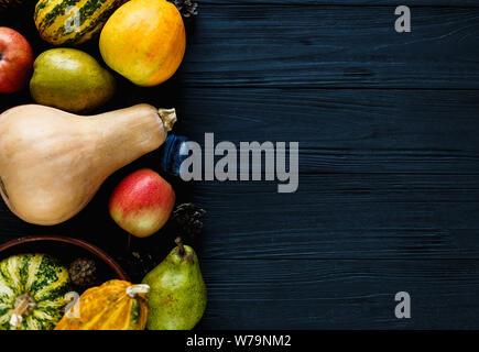 Pumpkins, pears, plums, apples on black wooden table, top view, free space for text. Thanksgiving day composition of vegetables and fruits on dark woo Stock Photo
