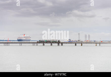 Hythe Pier on a cloudy grey day with the Queen Mary 2 leaving the Port of Southampton, Hythe waterfront, near Southampton Hampshire, England, UK Stock Photo