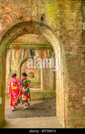 Young Japanese women dressed in traditional kimono take picture inside arches of ancient brick aqueduct at Nanzen-ji, Zen Buddhist Temple in Stock Photo