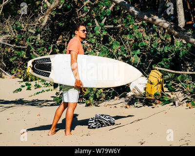 Male surfer checks the waves on the beach. Stock Photo