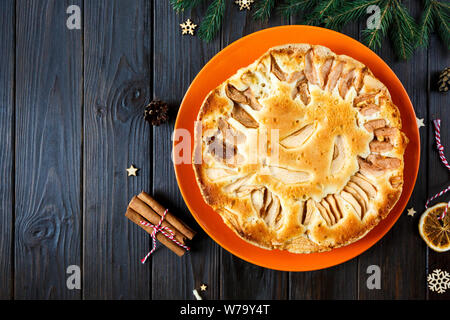fruitcake for Christmas decorated with apples on the orange plate with cup of coffee on the wooden table. Delicioius Homemade Pastry. New year Stock Photo