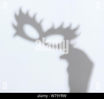 Shadow of face mask in hand on white wall background Stock Photo