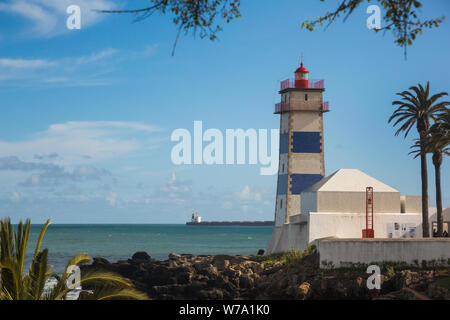 View of the towering blue and white striped Santa Marta lighthouse (Farol de Santa de Santa Marta) overlooking Cascais Bay at Cascais, Portugal. Stock Photo