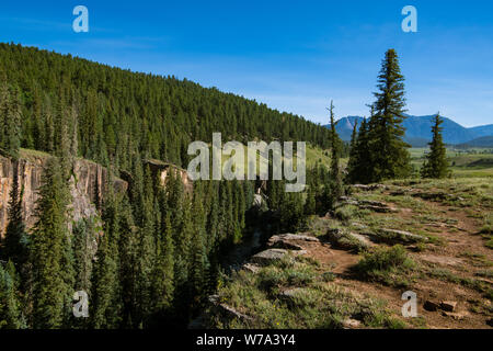 Canyon rim and cliffs above the Piedra River with the Rocky Mountains in the distance near Pagosa Springs, Colorado Stock Photo