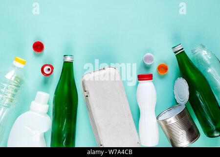 Flat lay of different wastes ready for recycling on green background. Plastic, glass, paper, tin cans. Social responsibility, ecology care concept Stock Photo