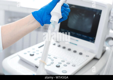 gynecologist puts a condom on the ultrasound sensor to examine the internal organs of the patient's pelvis. Stock Photo