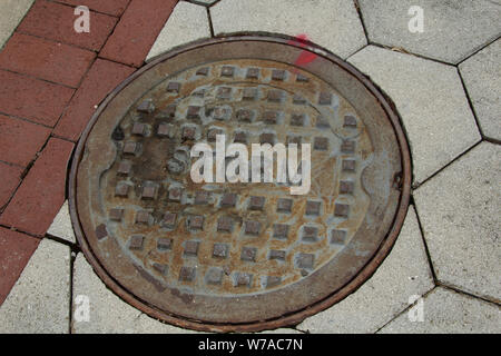 Storm drain cover in sidewalk Stock Photo