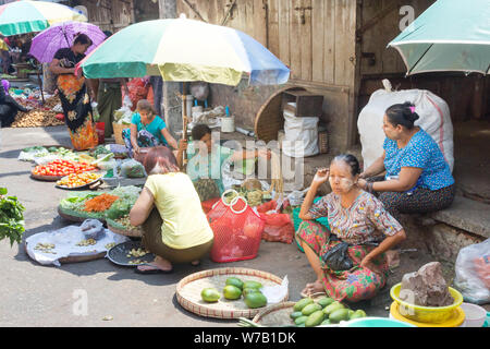 Yangon, Myanmar-May 4th 2014: Women wait for customers in a street market. There are many such markets in the city. Stock Photo