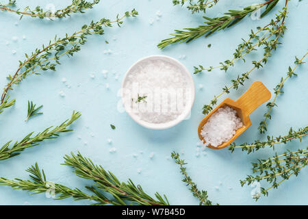 Coarse sea salt, fresh thyme and rosemary twigs on light blue background. Set of herbs and spices for cooking. Seasoning for vegetables, meat or poult Stock Photo