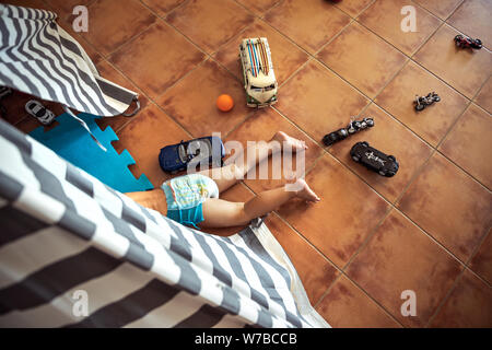 Baby boy playing at home, lying down in his tent, top view on little playful kid, happy carefree childhood Stock Photo