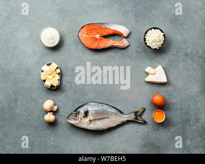 Vaitamin D sources concept with copy space in center. Fish, salmon, dairy products, eggs, mushrooms on gray stone background. Top view or flat lay. Stock Photo