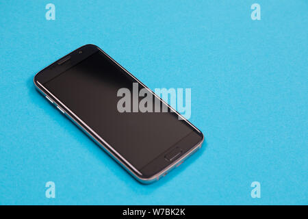 One black smartphone is lying on azure surface isolated Stock Photo