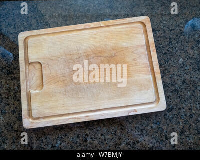 Isolated large wooden cutting board on a granite kitchen counter Stock Photo