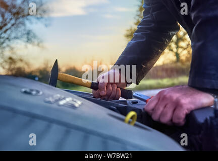 Thief wearing black clothes stealing a car Stock Photo