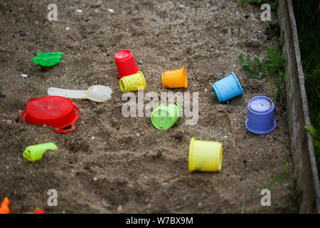 Plastic toys in a wet sand pit during a rainy day Stock Photo