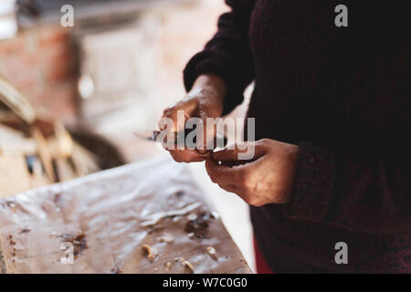 Details with the hands of an old woman peeling garlic for cooking Stock Photo