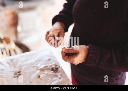 Details with the hands of an old woman peeling garlic for cooking Stock Photo