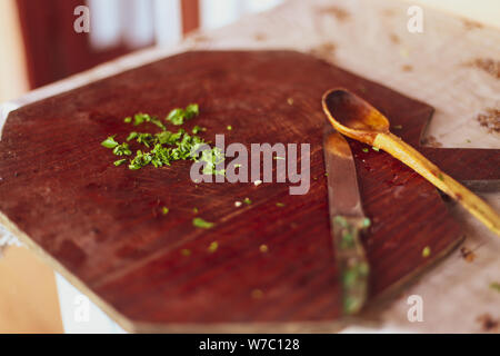 Shallow depth of field image with chopped parsley on a wooden cutting board, a knife and a wooden spoon Stock Photo
