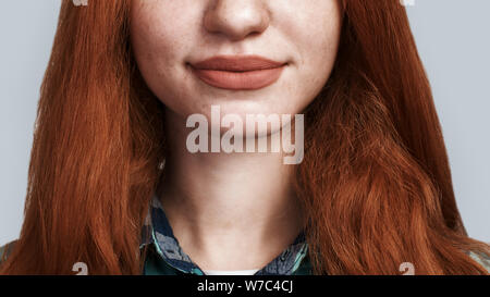 Studio shot of smiling cute young redhead lady while standing against grey background. Human emotions. Positivity Stock Photo