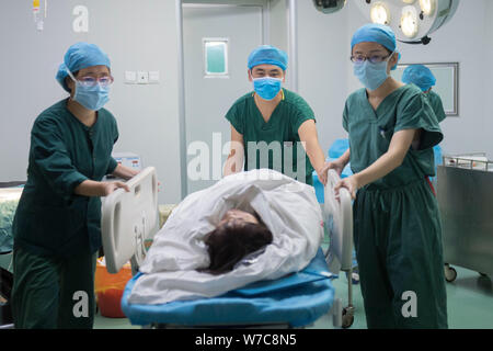 Qiao Rui, center, the sole male chief nurse at the Affiliated Hospital of Shanxi University of Chinese Medicine, pushes a patient out of an operating Stock Photo