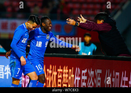 Cameroonian football player Christian Bassogog of Henan Jianye, center, celebrates with his teammate Hu Jinghang and their coach Guo Guangqi after sco