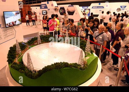 --FILE--People throng to look at the model of the world's largest radio telescope called FAST (Five-hundred-meter Aperture Spherical Telescope) during Stock Photo