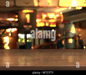 Blur bokeh background with empty wooden table top in night cafe Stock Photo