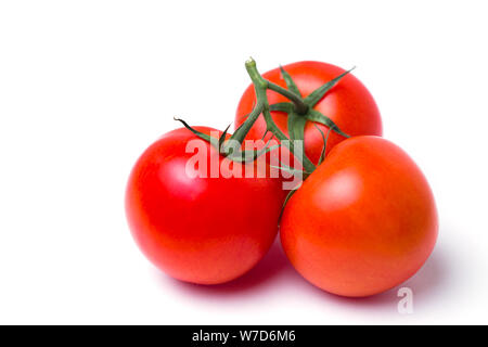 Closeup of three red fresh tomatoes in a pile in a green stalk on white isolated background Stock Photo