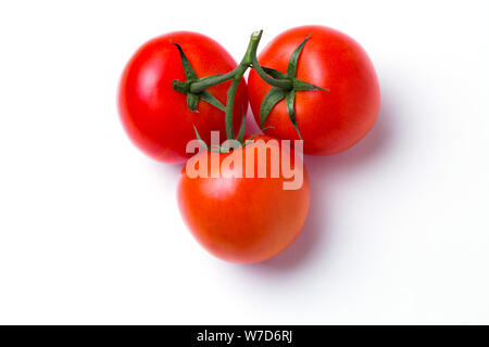 Closeup of three red fresh tomatoes in a pile in a green stalk on white isolated background, top view. Healthy diet, vegetarian food Stock Photo