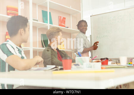 Positive delighted international teacher standing near board Stock Photo