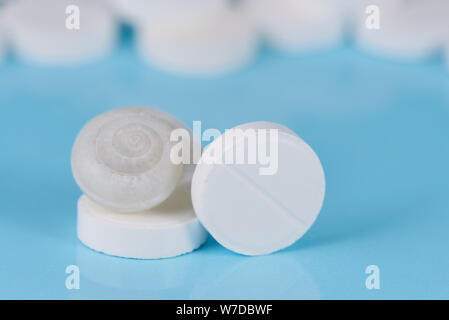White pills with a shell on a blue background. Stock Photo