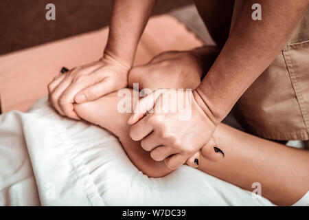 Feet of a beautiful woman massaging by hands of professional. Stock Photo