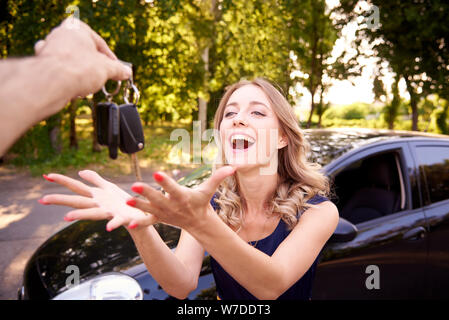 Happy young woman gets the keys to the car. Stock Photo