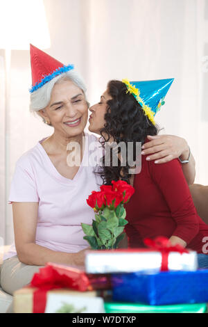 Young woman kissing her grandmother with bouquet Stock Photo