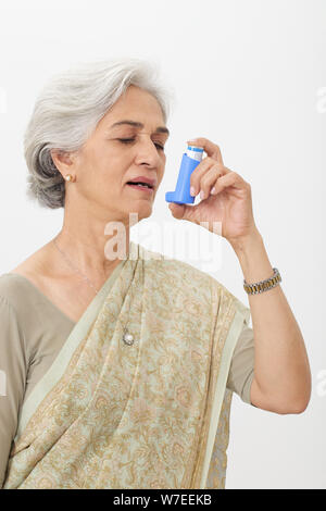 Old woman using asthma inhaler Stock Photo