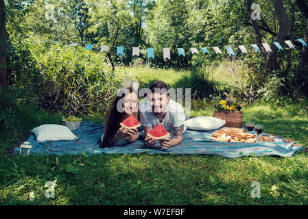 Young couple on a picnic laying down on a blanket and eating watermelon  Selective focus Stock Photo