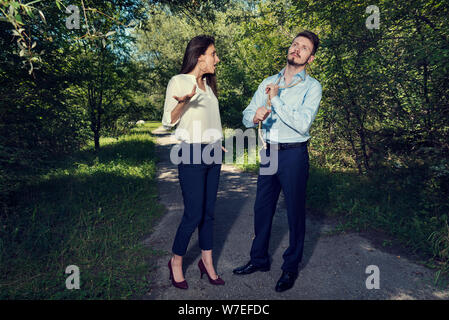 Business woman arguing with business man with rope loop on his neck in the city park Selective focus Stock Photo