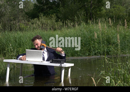 Young bearded millennial man tired of office work Doing stupid things, having fun in the workplace. Stock Photo