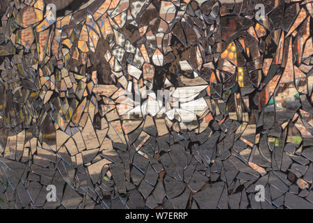 Cracked cement wall with dirty mosaic made from broken mirror pieces with distorted reflection in them. Abstract reflection in mirror splinters. Rough Stock Photo