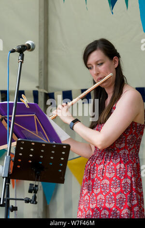 A young woman performer playing a flute Stock Photo