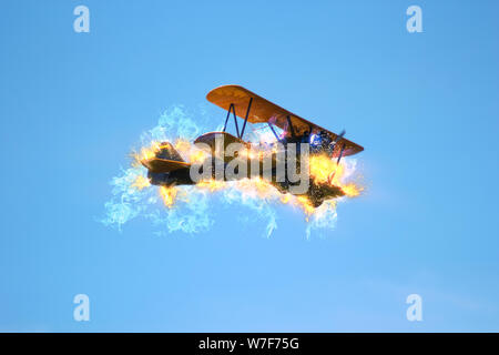 Digitally enhanced side view image of a burning biplane in flight Stock Photo
