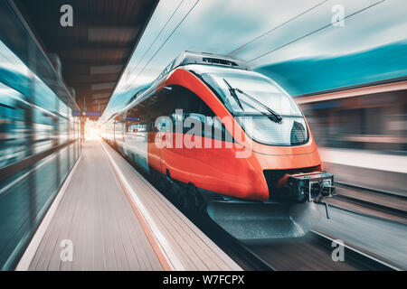 High speed orange train in motion on the railway station Stock Photo