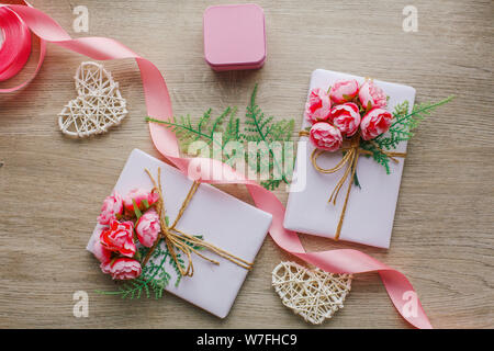Eco style gift wrapping. Composition with gift boxes decorated with green branch and rose. Stock Photo