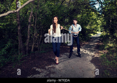 Business woman pulling one business man with rope in the city park Selective focus Stock Photo