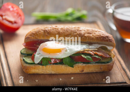 Sandwich with egg, bacon, vegetables and herbs Stock Photo
