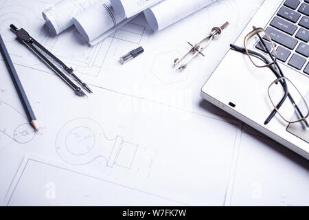 Laptop, glasses, pencil, compass and rolls drawings on the table in engineering Stock Photo