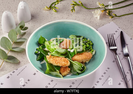 Fried breaded crispy chicken slices in a blue plate served on a table with a white tablecloth. Stock Photo