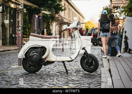 Old small white scooter parked in a cobbled street Stock Photo